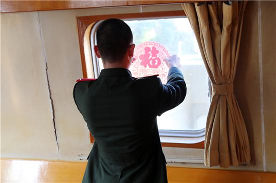 新兵把“福”字窗花贴上船窗。